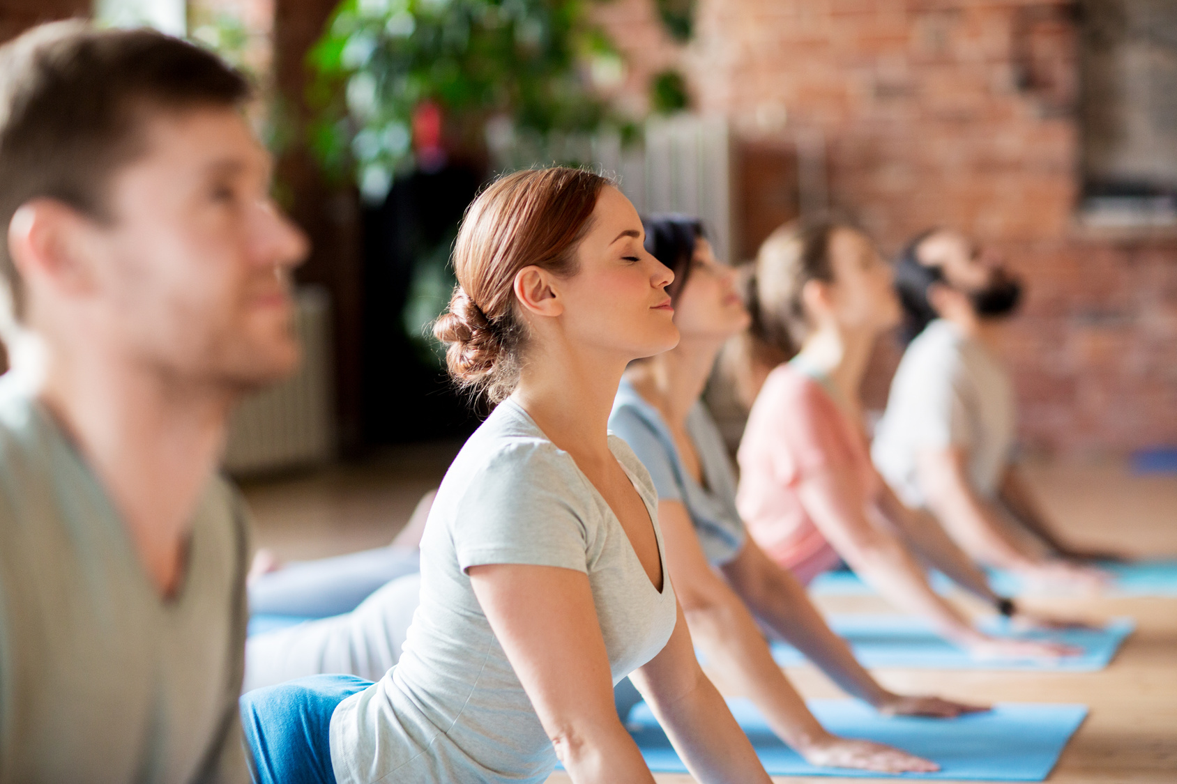 group of people doing yoga cobra pose at studio